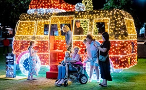 Several people gathered at a van covered in festive bright lights