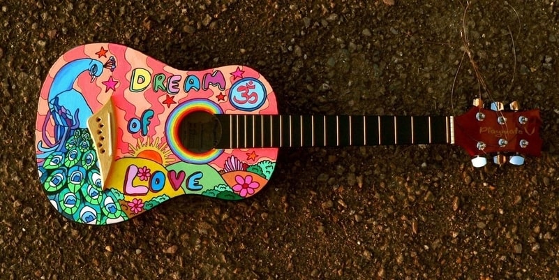 Colourful cartoon drawing on a guitar pictured lying face up on a road.