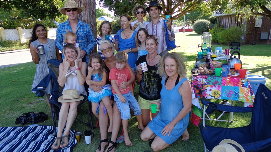 A group of neighbours gathered around a tree having a picnic