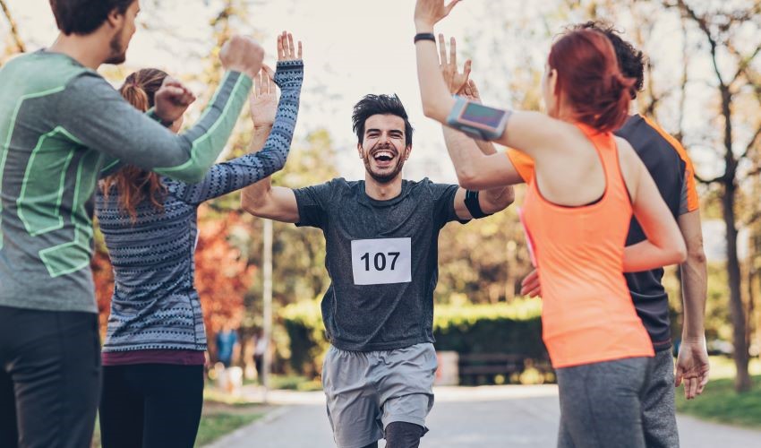 man running outside in a race with other people cheer him on