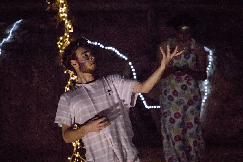 Actor performing at night with fairy lights in the background