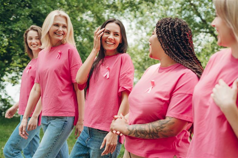 Five women walk side by side in pink shirts  