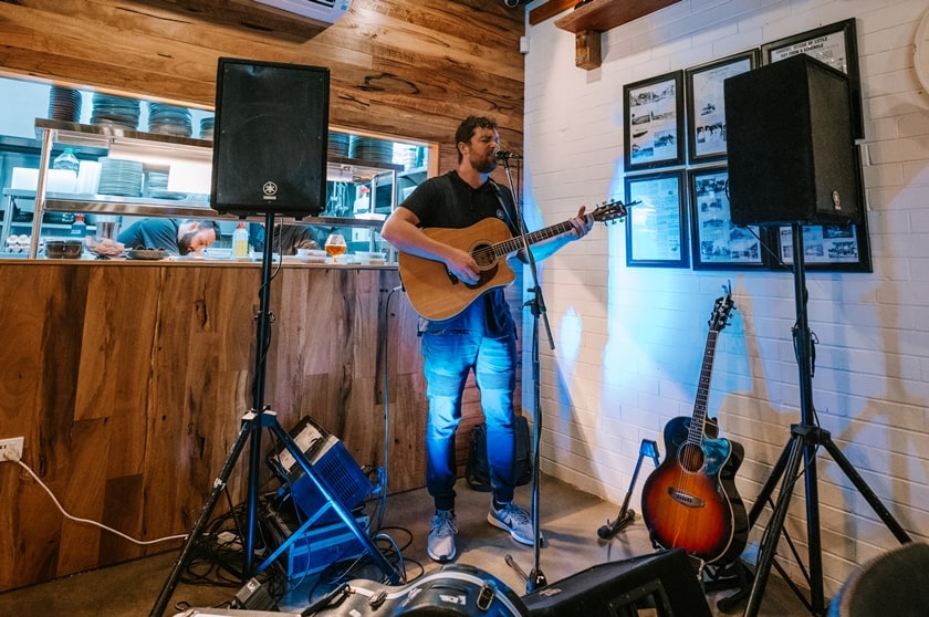 Solo male acoustic artist playing guitar and signing in a restaurant