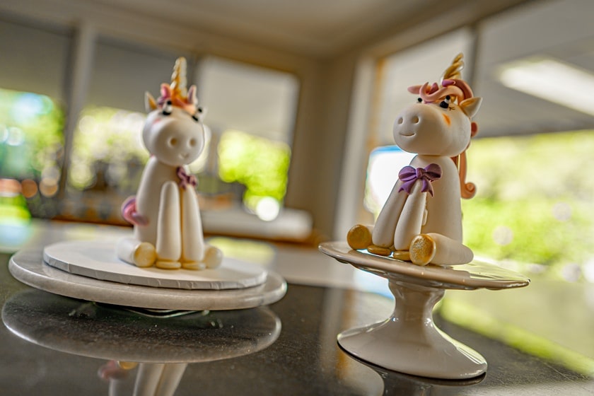 Two white unicorn fondant cake toppers sitting on pedestals.