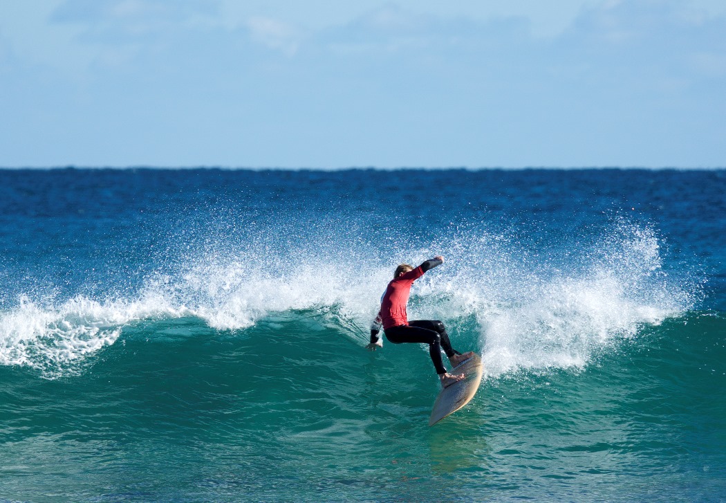 man in red rashie surfing a wave
