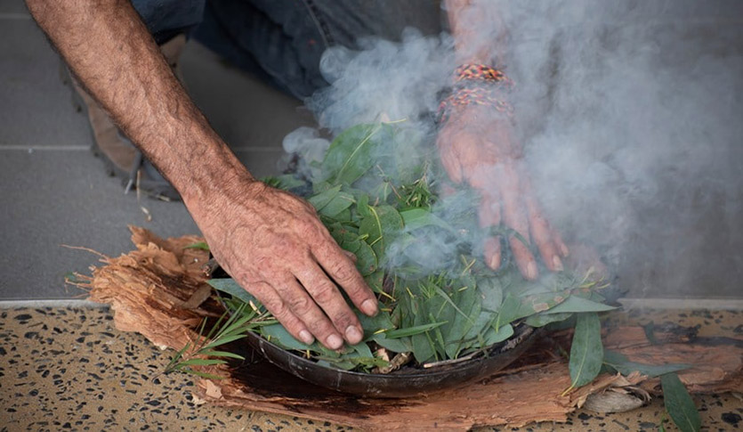 Gentleman's hands over smoking plants as part of a traditional smoking ceremony