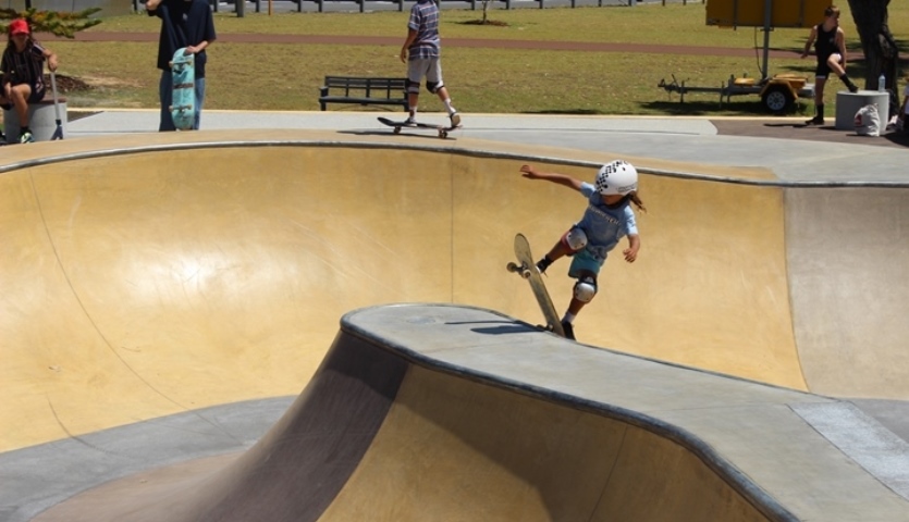 A child doing a kickflip on a skateboard at the skate park