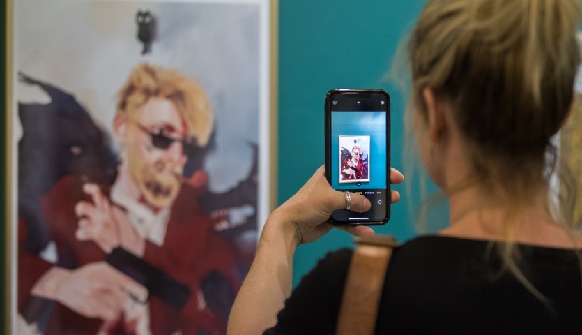 A painting of a man with a gun as viewed through a phone screen.