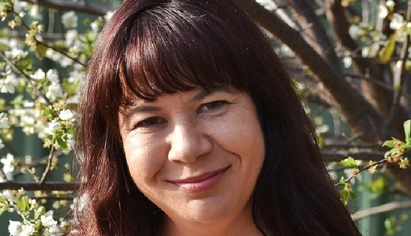 close up headshot of author Sascha Wasley with trees and leaves as a background.