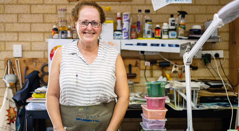 An artist stands in studio with art materials