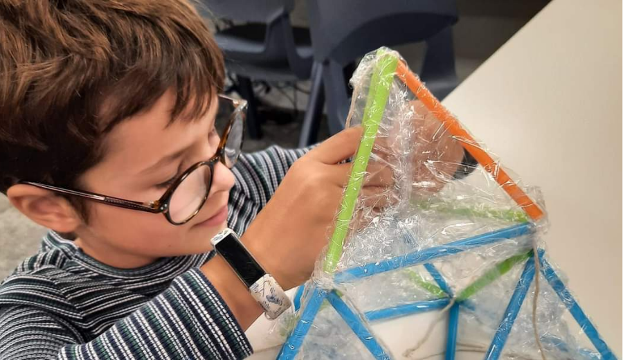 Close-up of a child using straws to build a structure