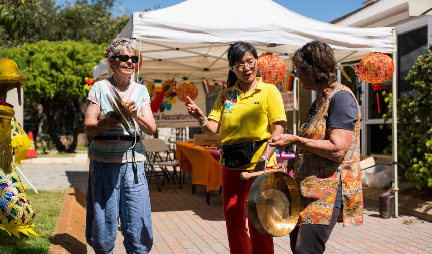 Two ladies holding instruments while an instructor shows them how to play