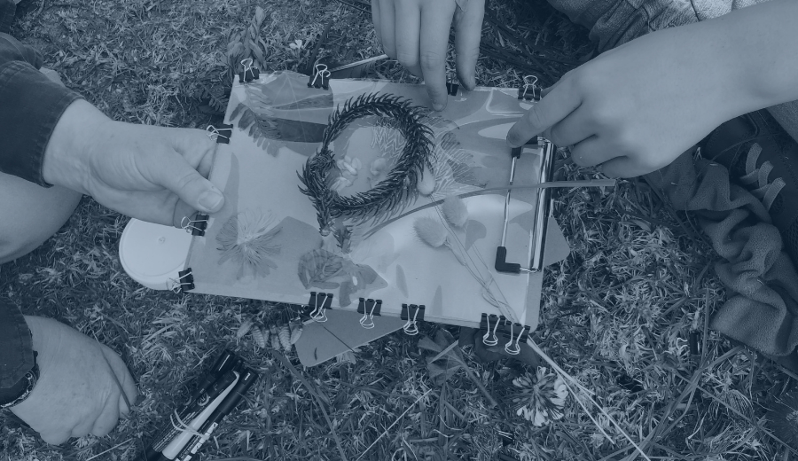 two pairs of hands holding a clipboard, with plant materials piled on top