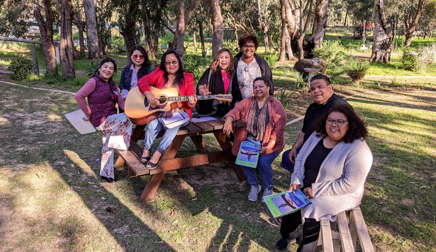 A group of people sat together on a bench, smiling towards the camera