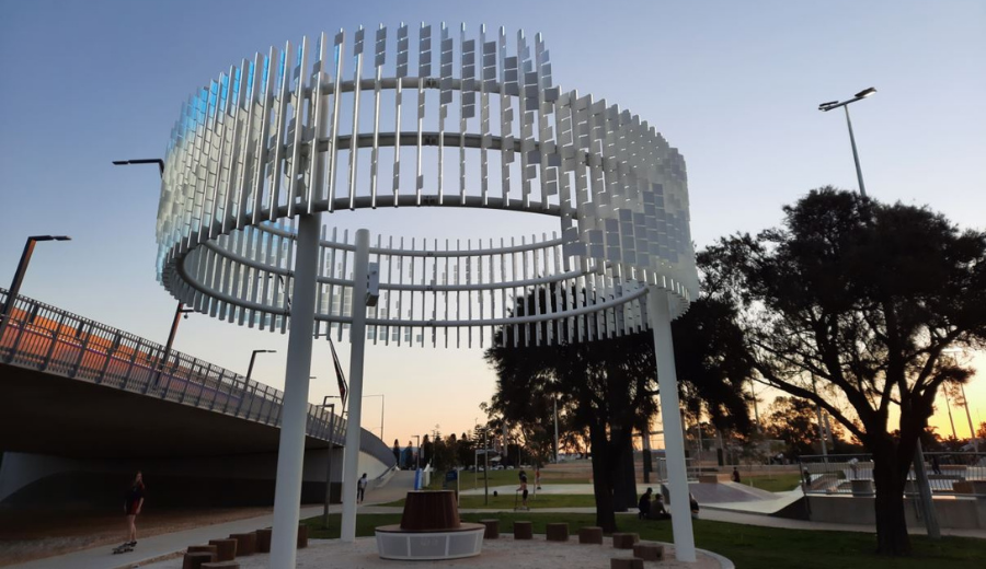 Large white helix structure supported by tall white poles, photographed at sunset