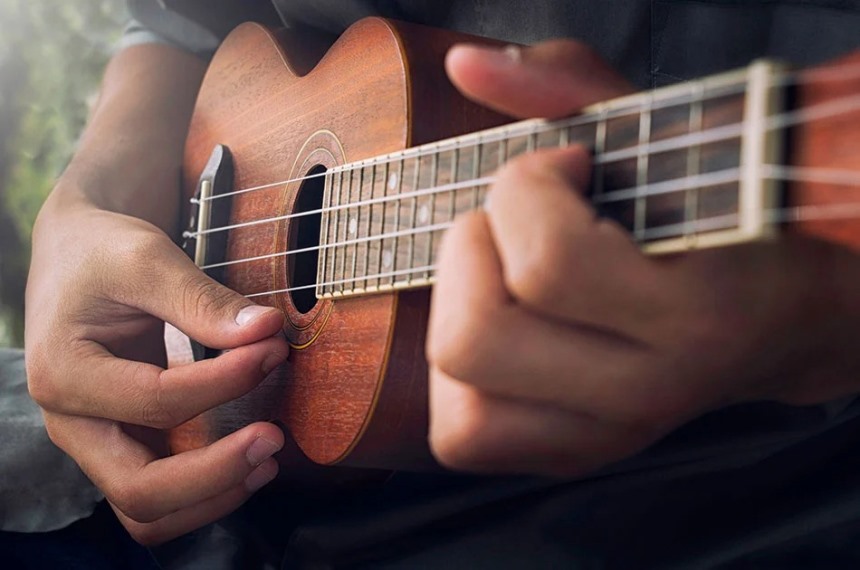 person playing a ukulele with their hands