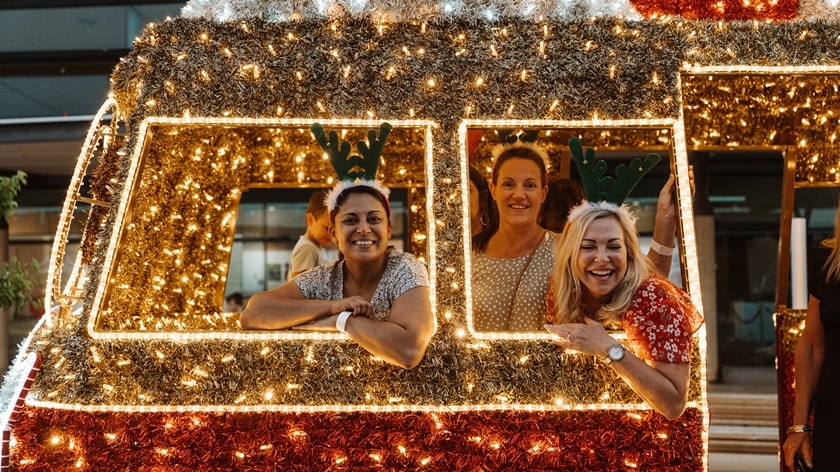 Three women in the Christmas Combi while it is lit up on the Christmas lights trail