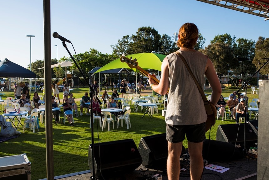 Musical Fruit performance Performer on stage with guitar singing to the public looking on