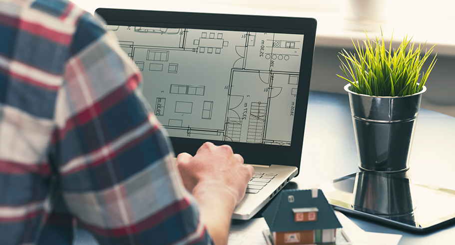 Man looking at building plans on his laptop