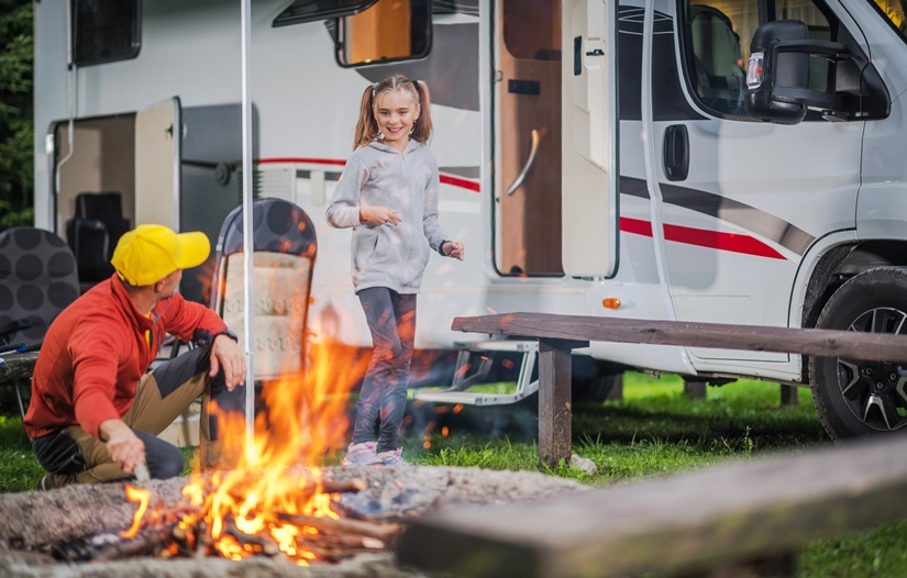 Family camping with a campfire outside a caravan