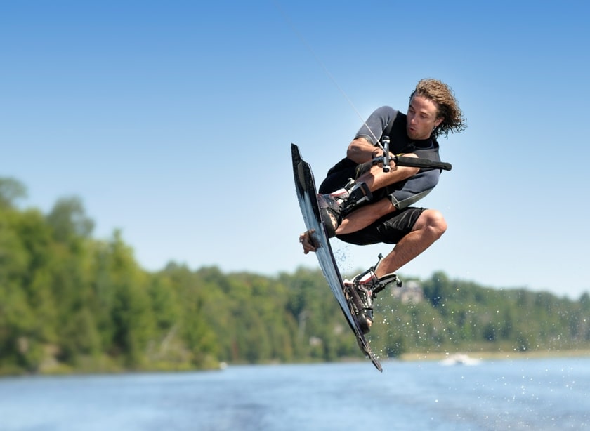 Man doing a jump while wakeboarding on a sunny day.