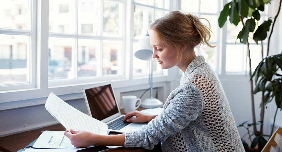 Young lady paying bills online at desk Young lady paying bills online at desk