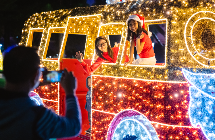 Two people pose for a photo leaning out the windows of the Kombi van light installation