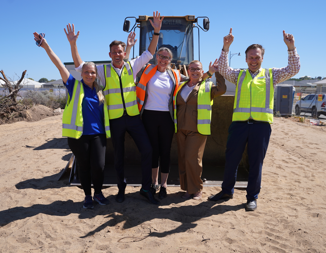 Community representatives stand side by side, hands in the air to celebrate new community centre