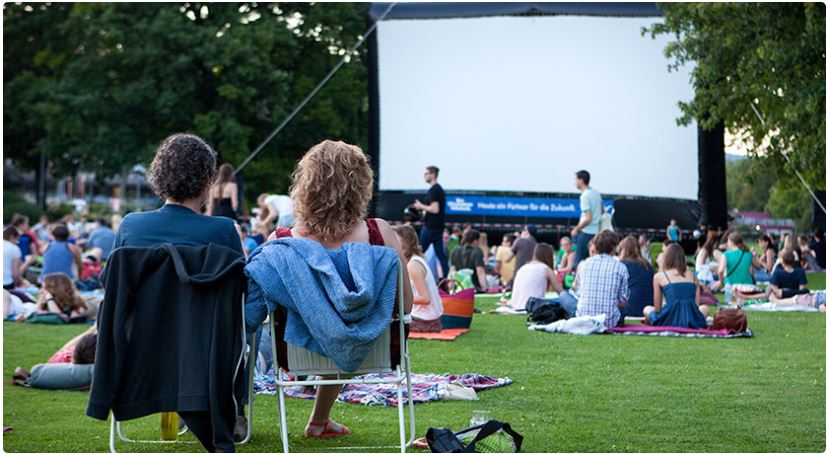 People on deckchairs and blankets enjoying outdoor movie