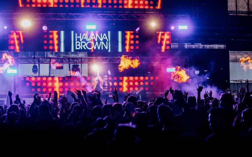 Crowd in the foreground and DJ in the background on stage