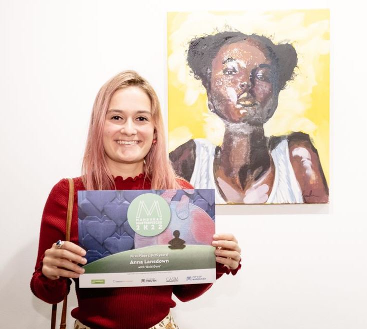 Young artist Anna Lansdown stands next to her artwork with her winner's certificate