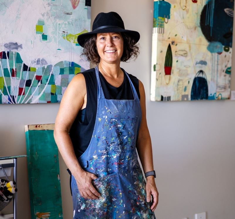 Artist stands with artworks in background