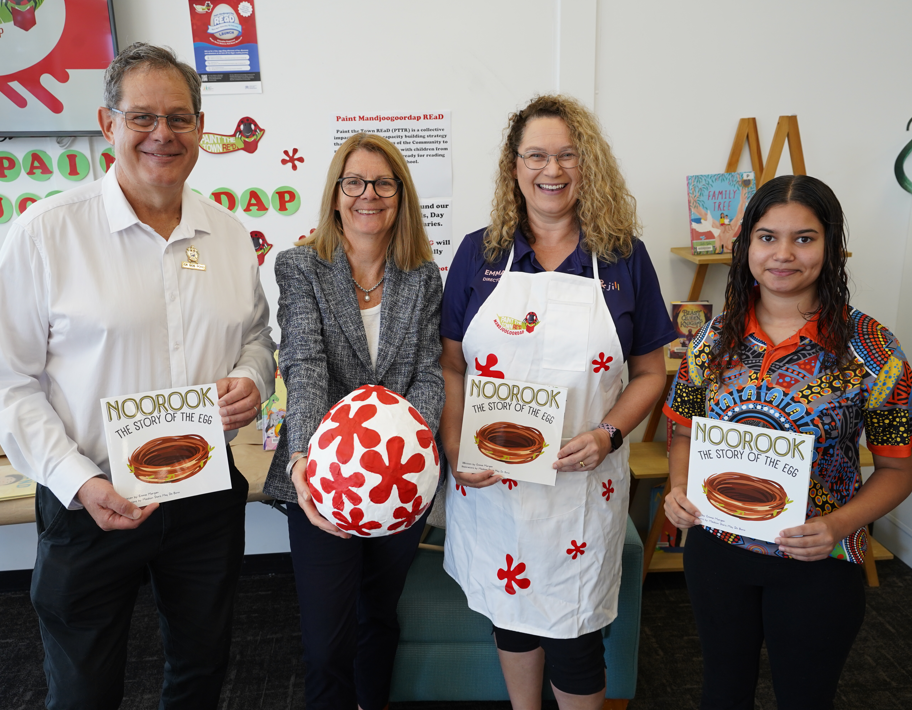 Four people stand side by side with books and the reading egg