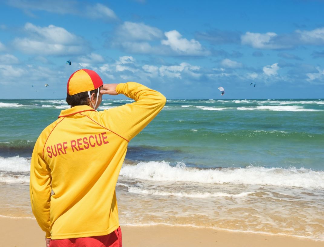 Surf life saver stands and looks out over beach