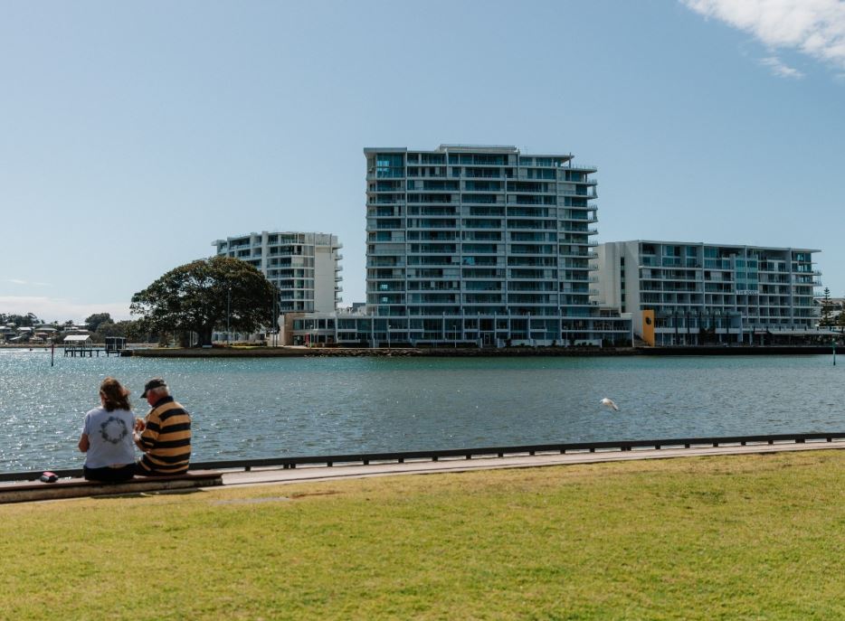 Two people sitting on Eastern Foreshore estuary walkway, overlooking estuary