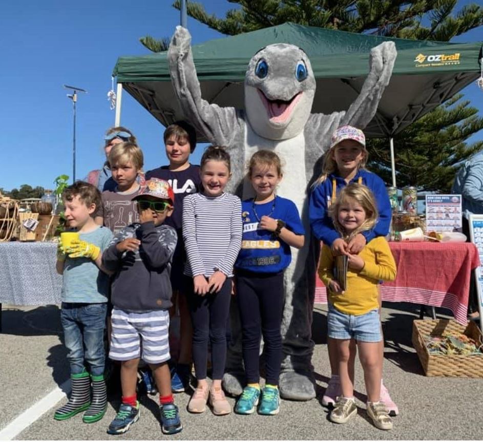 group of children stand with dolphin mascot at community clean up