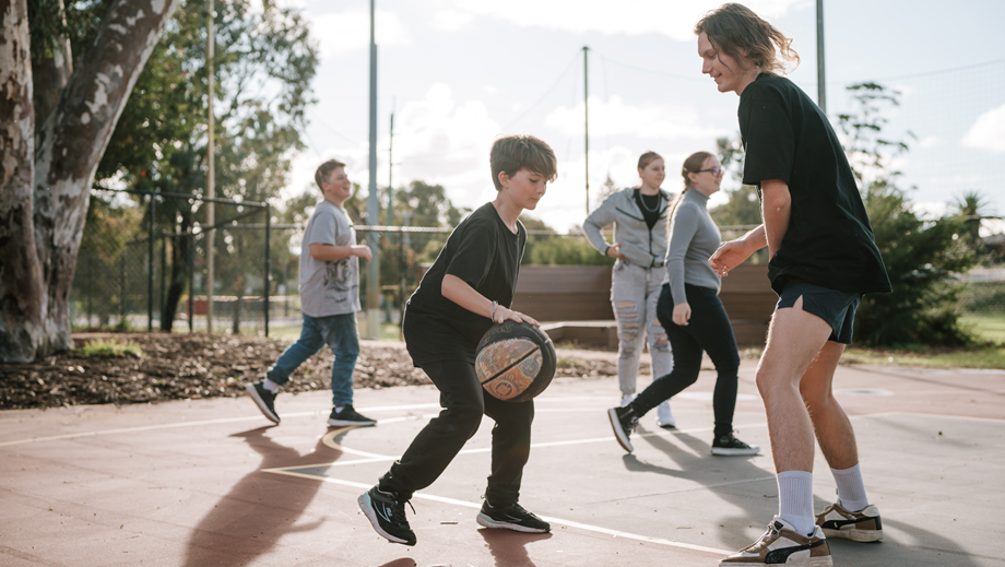 A group of Youth playing basketball on an outside court.
