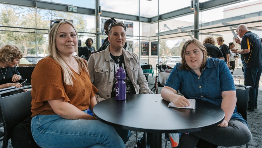 Three people sitting at a table at an event.