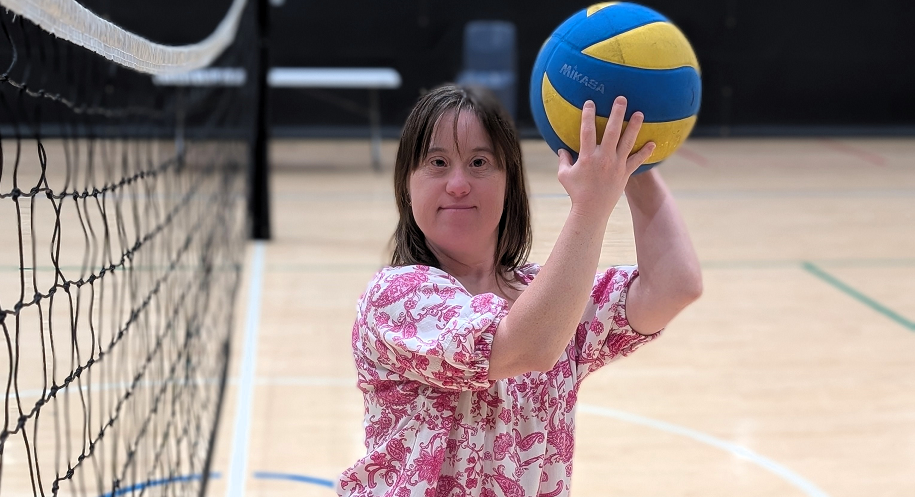 Young lady holding a volleyball above her head