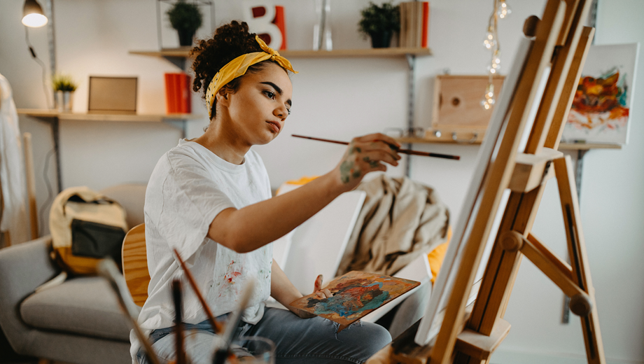 Young lady painting on a canvas on an easel.