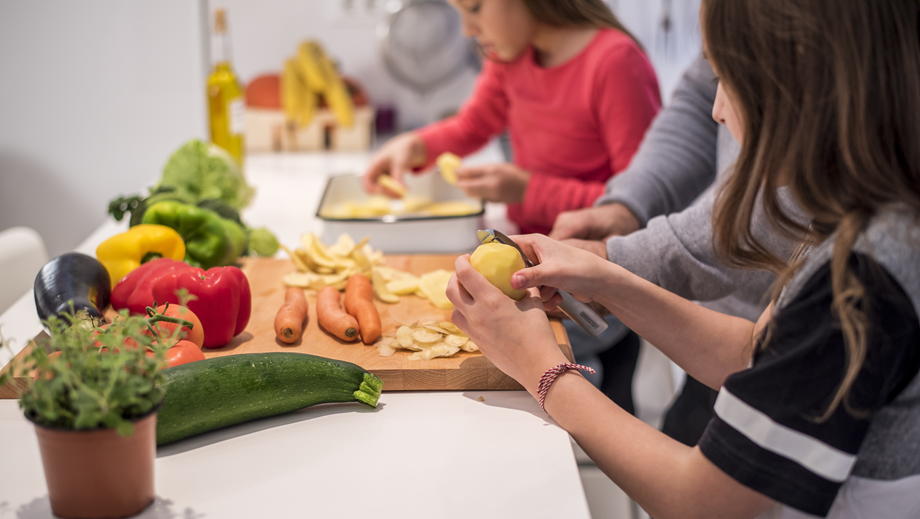 Young girl cooking in a kitchen with her father.