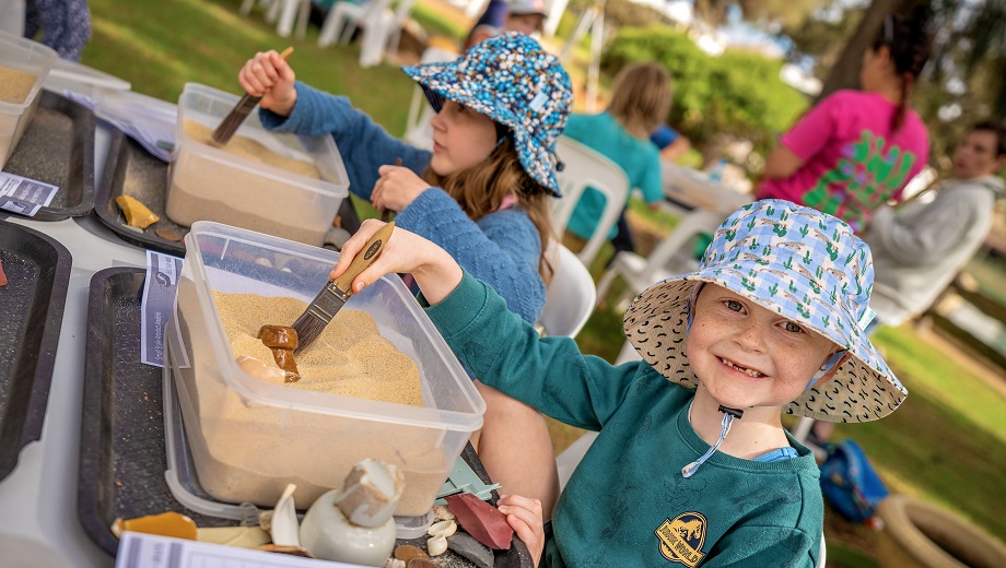 Two kids digging for artefacts in sand containers