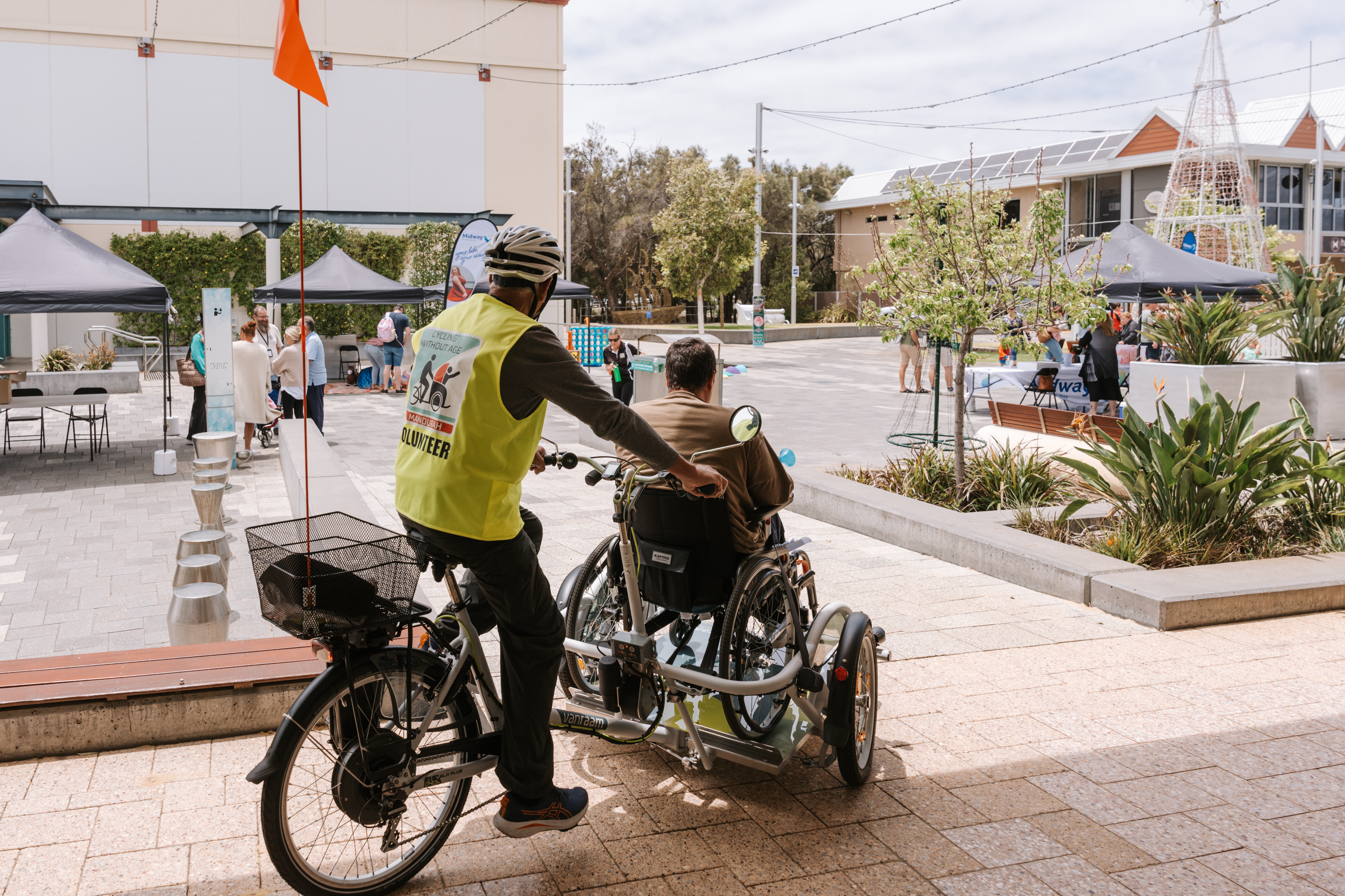 A Cycling without Age Volunteer taking a community member around the City centre. Their backs are to the camera as they cycle away.