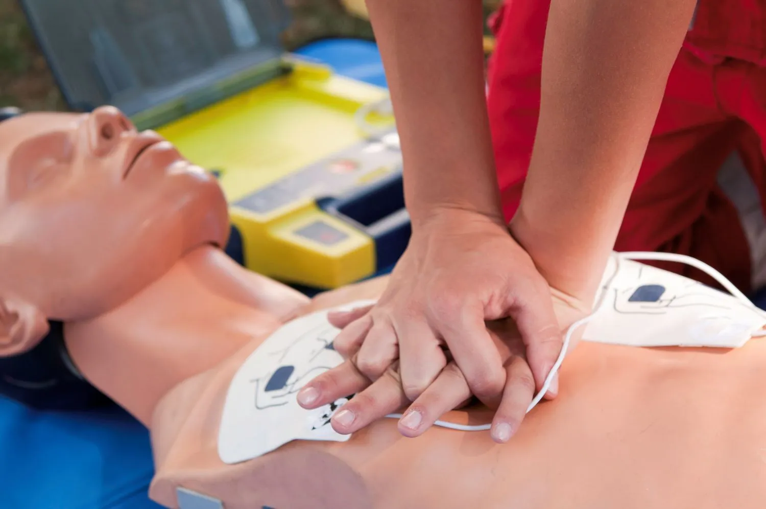 Hands pressing down on CPR dummy chest learning CPR.