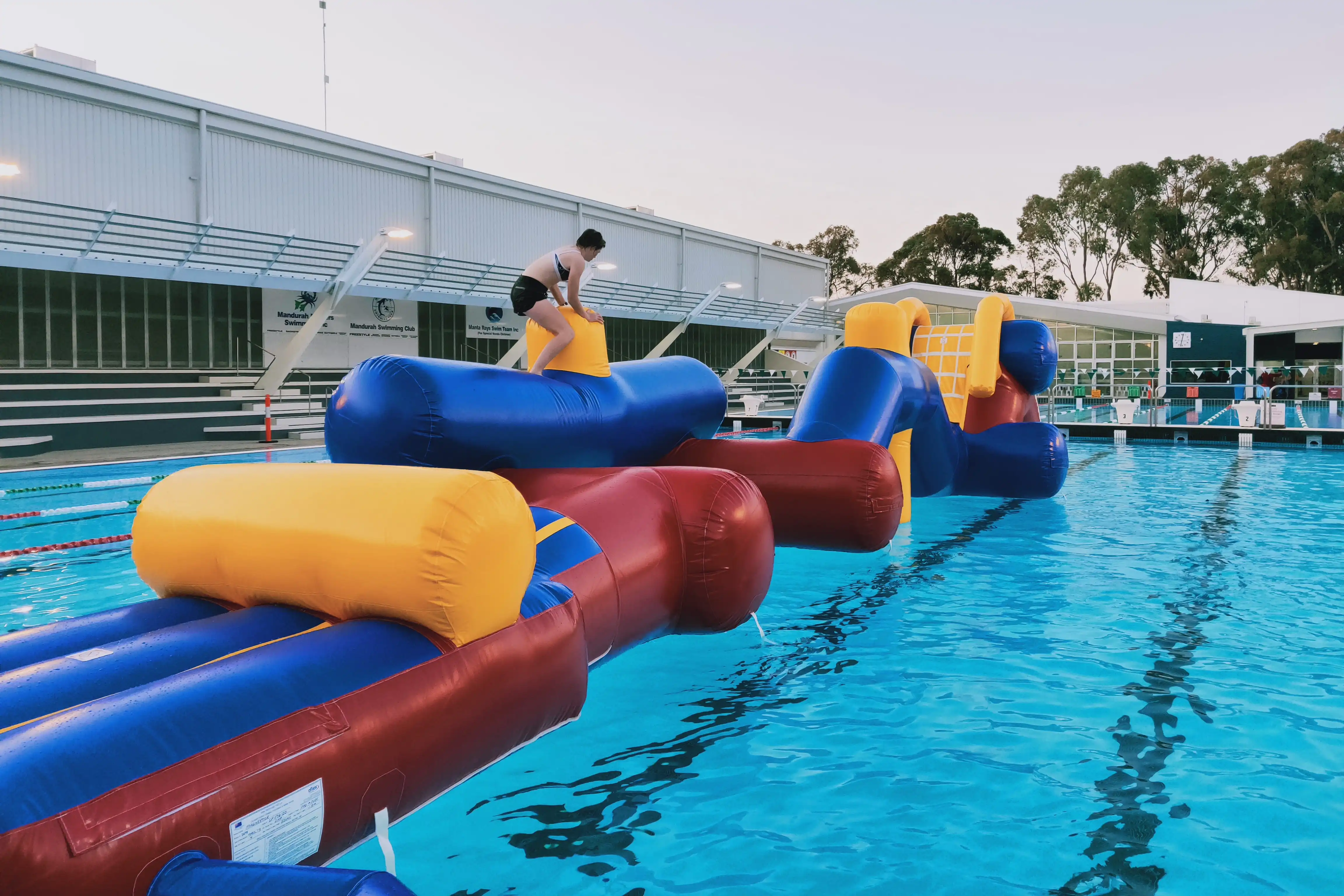 Person on giant inflatable in outdoor pool.