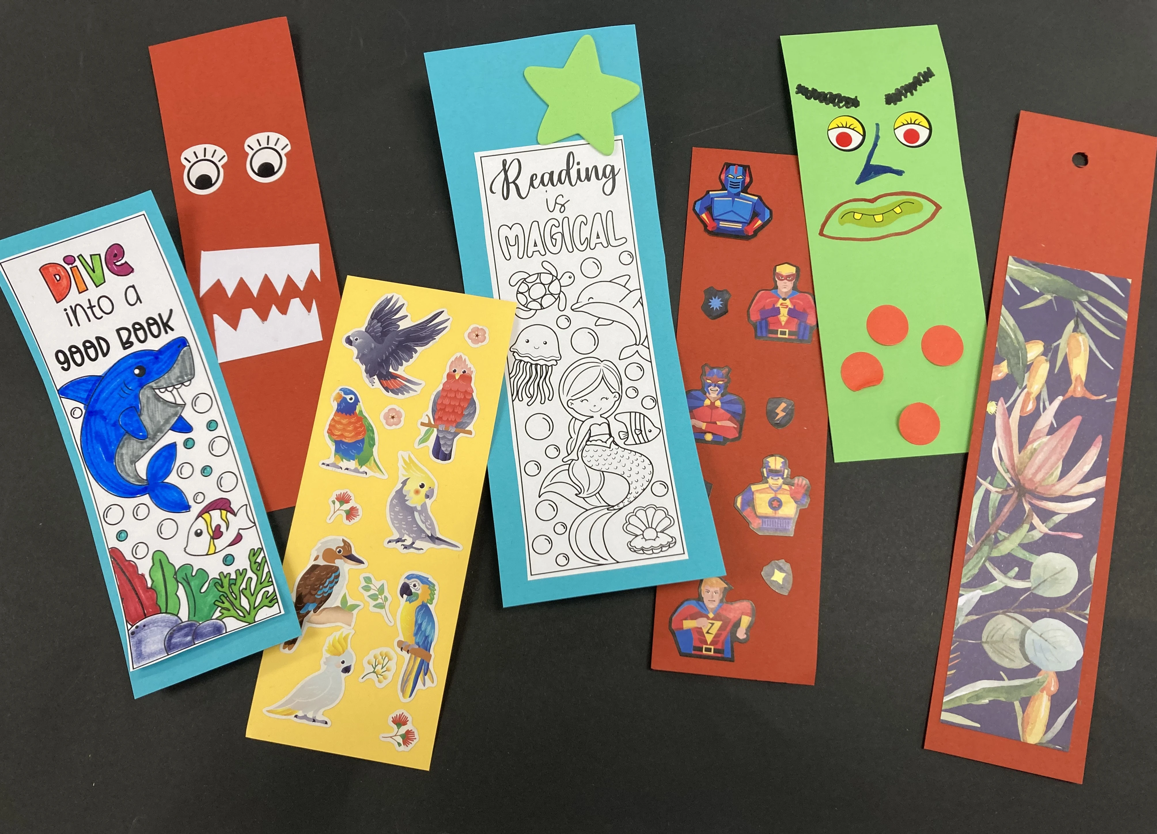Different colourful bookmark designed, lying next to each other on top of a black background.