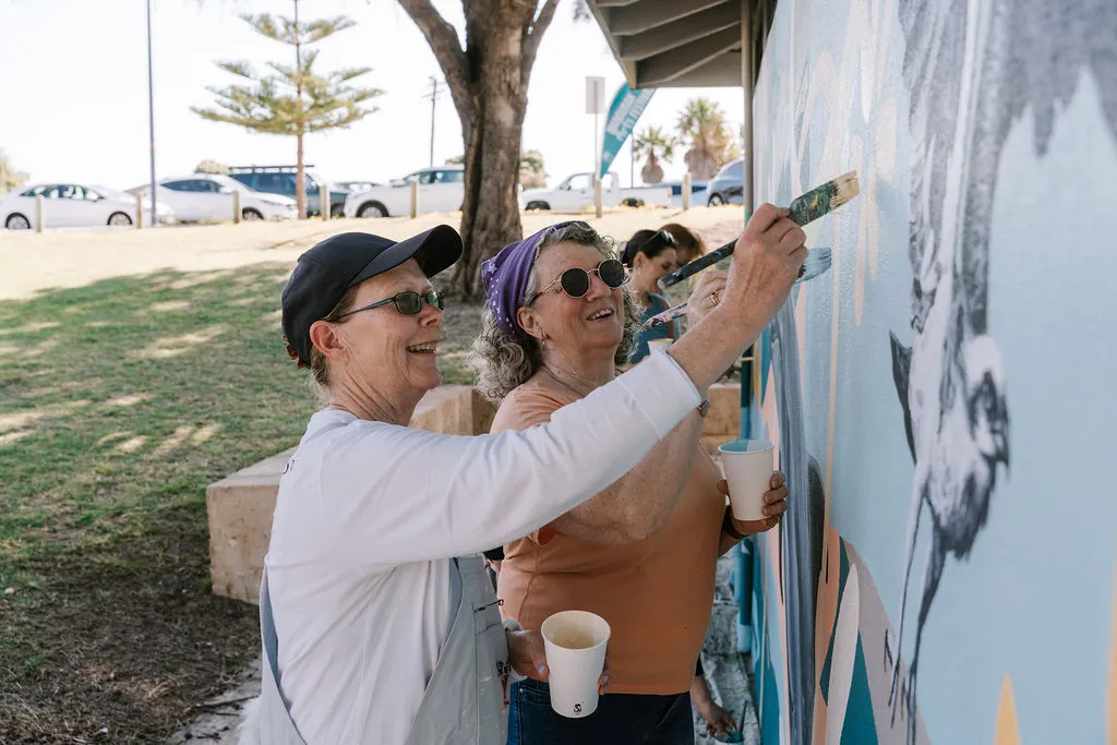People painting a large outdoor mural together.